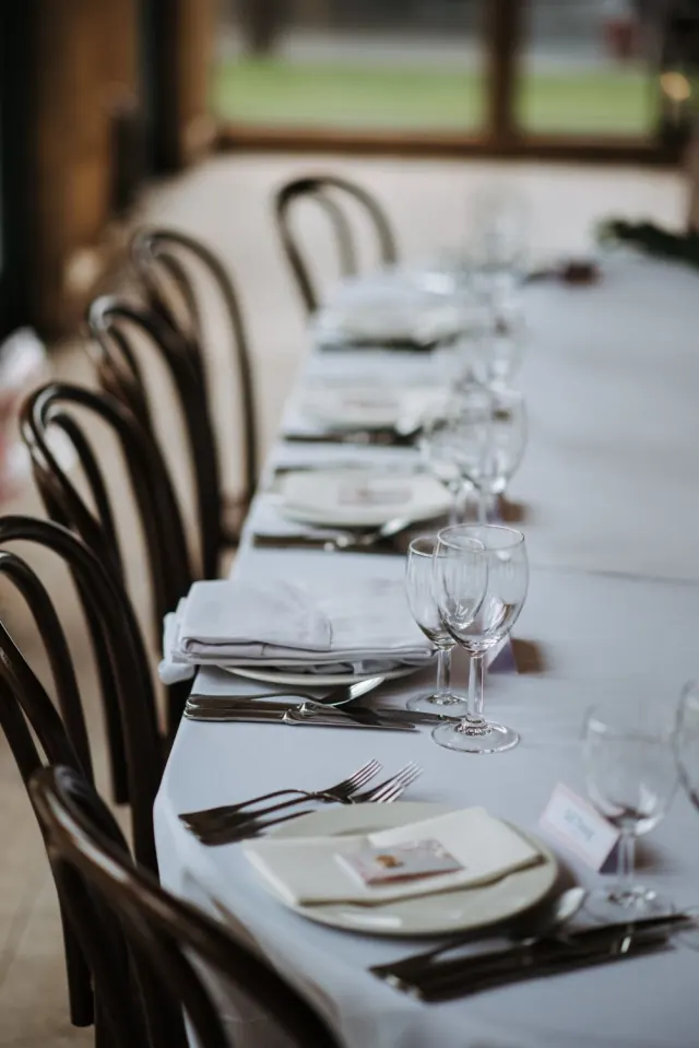 Longue table dressée, chaises bistrot, verres à pied et marque-places